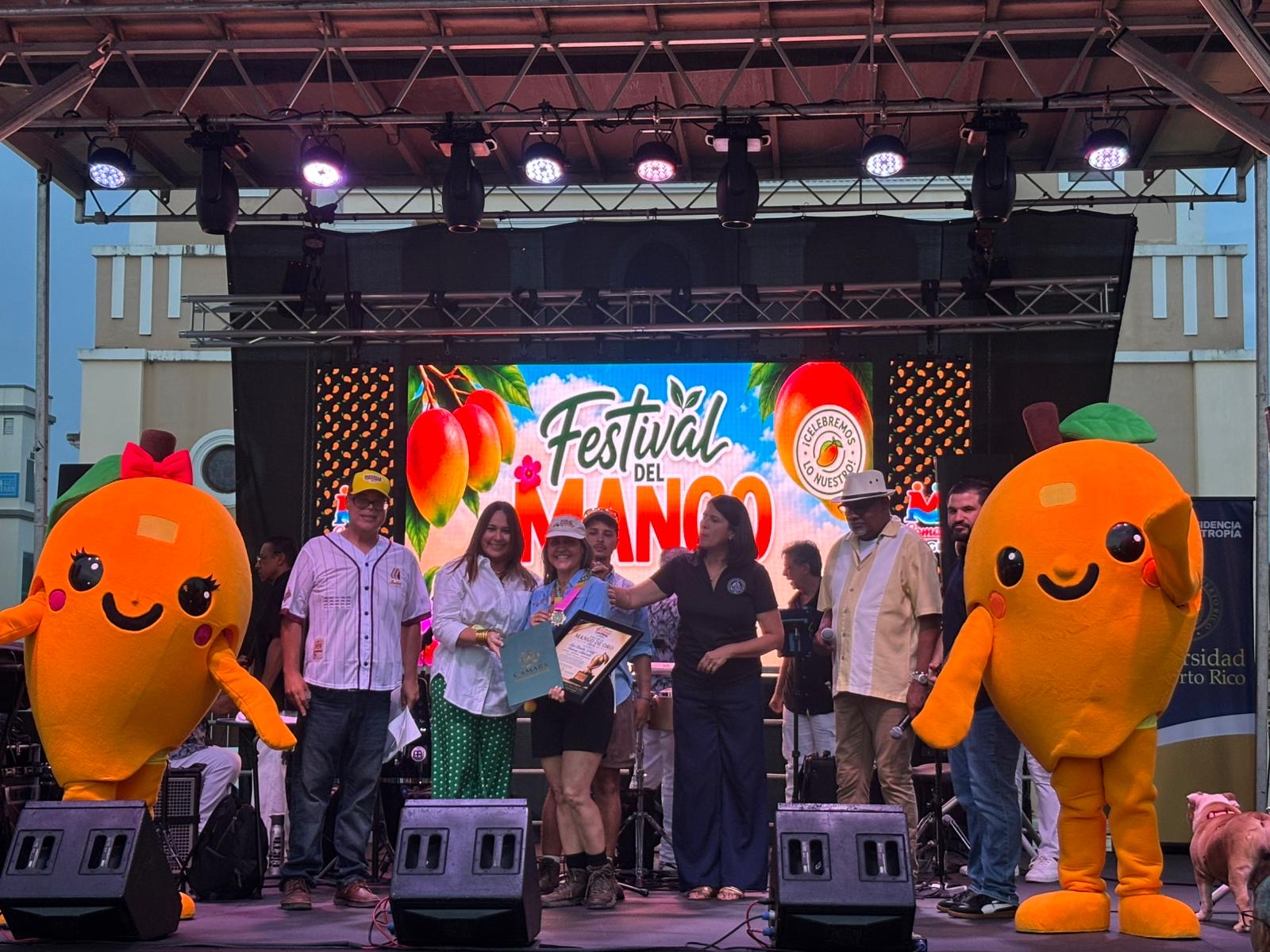 Ceremonia Premio Mango de Oro 2026 — grupo en el escenario con mascotas del festival