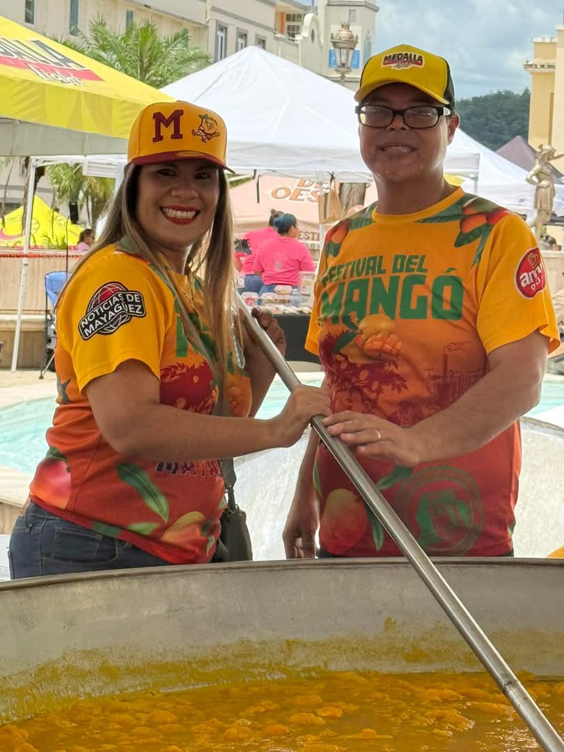 Voluntarias con camisas del Festival del Mango revolviendo la paellera gigante